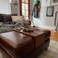 brown leather ottoman with a custom fitted wood tray to set remotes, drink, phones, etc. on