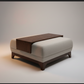 A modern upholstered ottoman or low bench with a dark wood tray table top, shown in a clean studio setting with a warm spotlight on a light gray background.