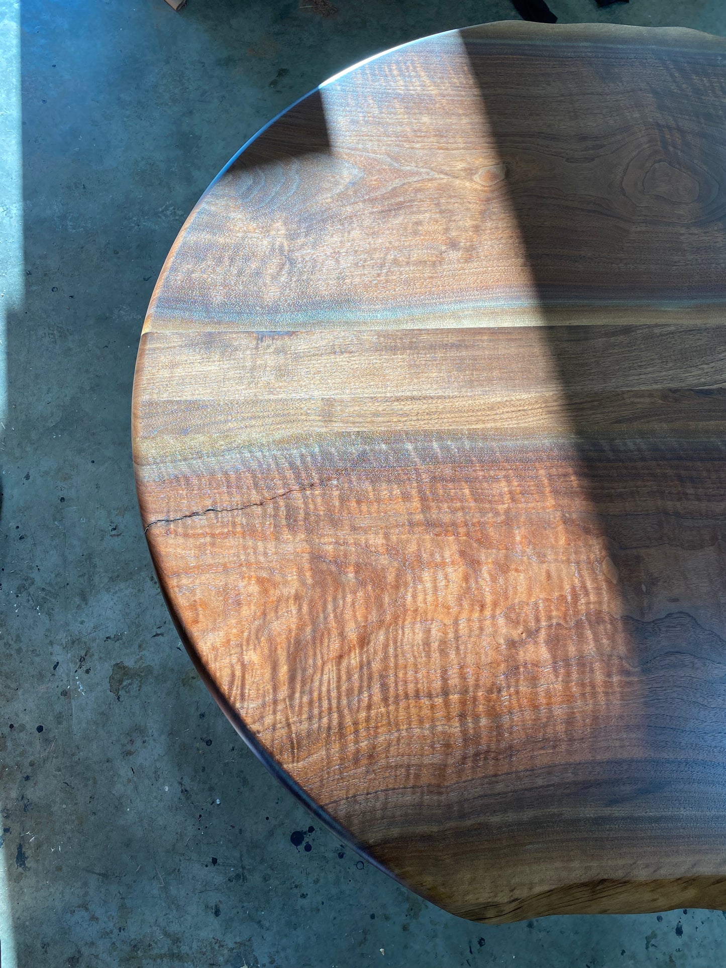 one of a kind round dining table with natural walnut slab slab made in columbus ohio, tulip base, gloss black tulip base, walnut live edge, walnut slab, walnut dining table, hardwood dining table, handmade dining table in ohio, made in use, made in america, local business, small business, luxury furniture, bespoke furniture, walnut in the sun, figured walnut grain, beautiful rays curls 