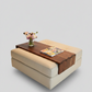 A modern beige upholstered ottoman or coffee table with a dark wood top panel, styled with a small vase of flowers and a magazine, on a solid light gray background.