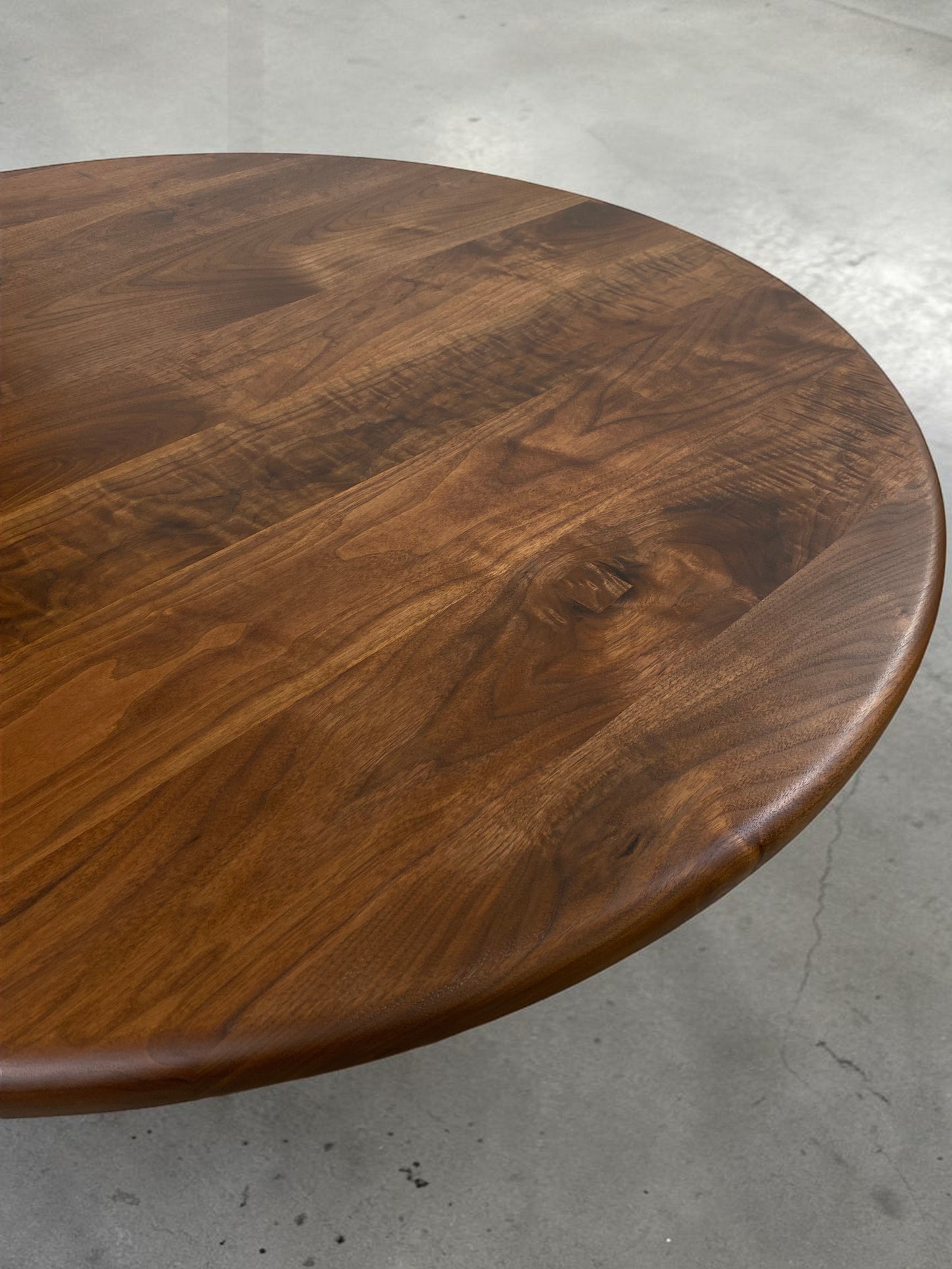 walnut wood round dining table with black metal tulip base, handmade in USA, made in america, made in ohio, solid walnut dining table with pedestal base, walnut table top closeup 